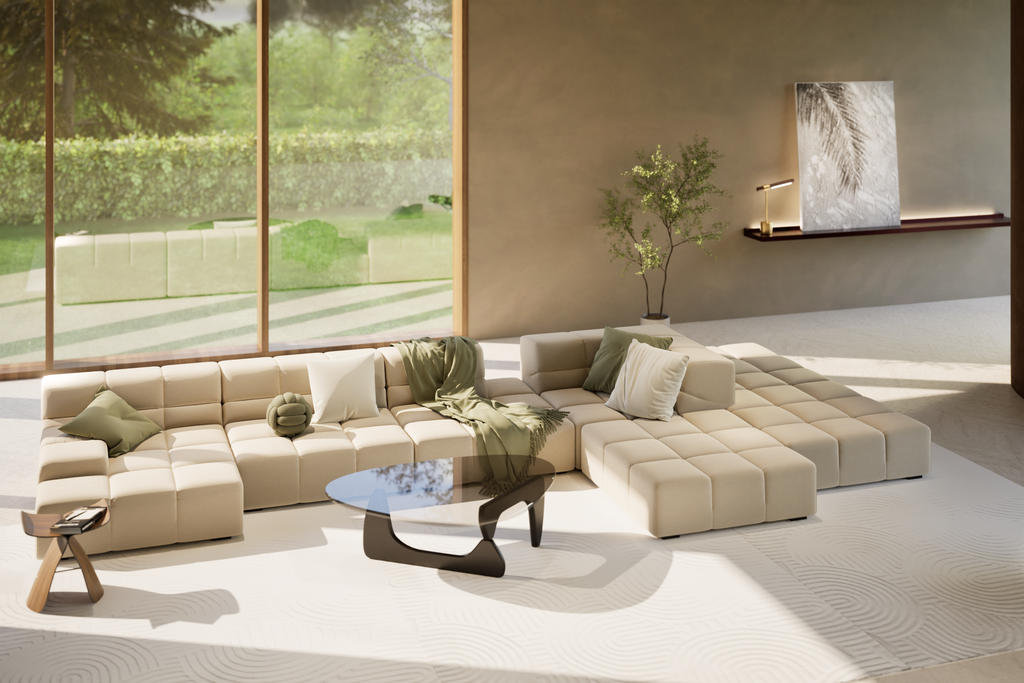 A modern living room featuring a beige modular sofa with plush cushions and green accents, complemented by a sculptural black coffee table and large floor-to-ceiling windows overlooking a lush garden.